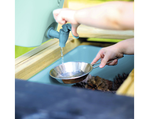 Un enfant verse de l''eau d''un robinet dans une casserole en métal sur une table de jeu.
