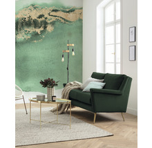 Salon lumineux avec canapé vert, table basse et papier peint à motifs