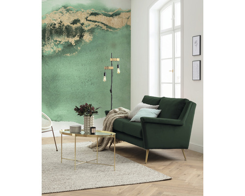 Salon lumineux avec canapé vert, table basse et papier peint à motifs