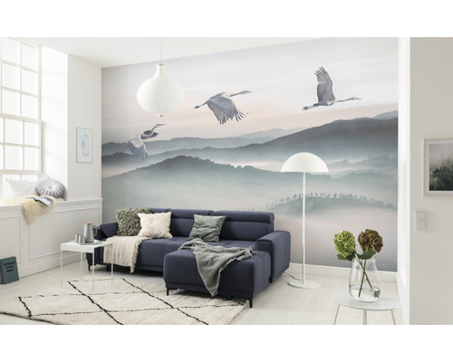 Salon avec papier peint photo paysage de montagne et grues, canapé, tapis et décoration.