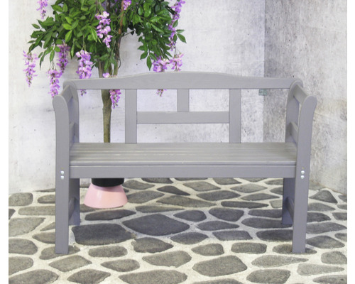 Graue Gartenbank aus Holz vor einer Steinwand