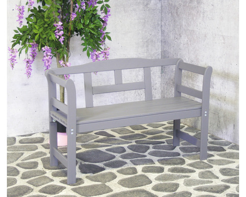 Graue Holzgartenbank mit Rückenlehne und Armlehnen neben einer Kunstpflanze