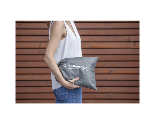 Eine Frau hält eine graue Tragetasche mit dem Campingaz Logo