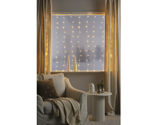 Salon confortable avec guirlandes lumineuses, rideaux, fauteuil et table d''appoint pour une ambiance chaleureuse.