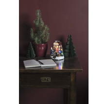 Dekoratives Arrangement mit Schreibtisch, Notizbuch, Stift, Weihnachtsbäumen und beleuchteter Weihnachtsszene