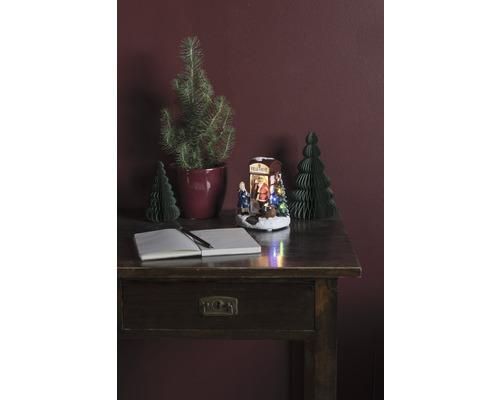 Dekoratives Arrangement mit Schreibtisch, Notizbuch, Stift, Weihnachtsbäumen und beleuchteter Weihnachtsszene