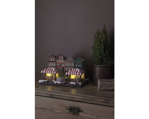 Weihnachtsmarktdorf mit Beleuchtung und dekorativen Häusern auf einem Tisch