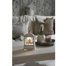 Lanterne décorative avec motif de Noël sur une table, entourée d''accessoires d''intérieur pour une ambiance festive