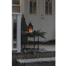 Lanterne décorative avec effet de flamme sur une table devant une porte d''entrée en hiver.
