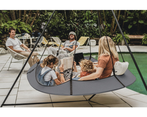 Szene mit einer Familie, die sich in einem Hängesitz entspannt, der an einem Gestell im Freien hängt