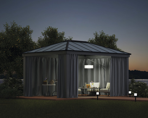 Pavillon avec rideaux, table et chaises sur une terrasse de nuit