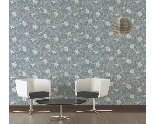 Une pièce avec un papier peint bleu à motifs floraux, deux chaises et une table.