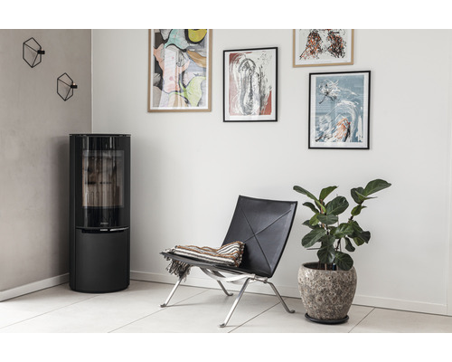 Wohnzimmer mit Kaminofen, Sessel, Zimmerpflanze und Wanddekoration