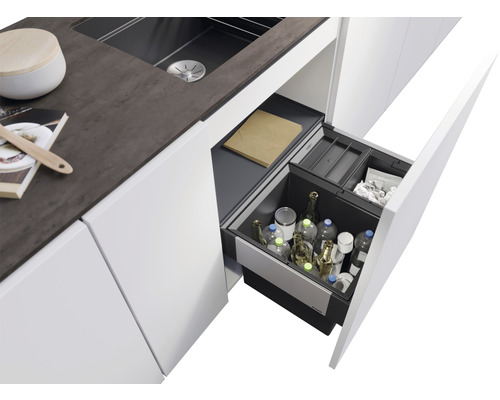 Évier de cuisine avec tiroir coulissant ouvert rempli de bouteilles et de bacs de tri des déchets.