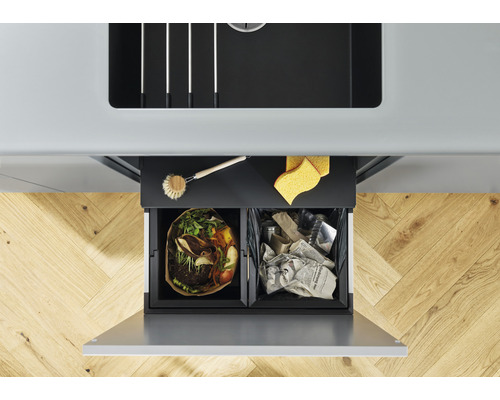 Vue de dessus d''un conteneur de tri des déchets à deux compartiments sous un évier, rempli de déchets organiques et de vieux papiers.