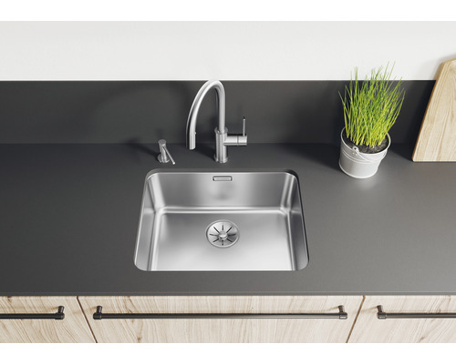 Scène de cuisine avec évier, robinet, distributeur de savon et décoration sur un plan de travail