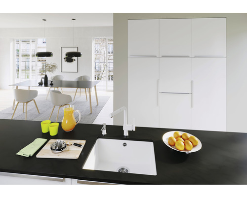 Salle à manger lumineuse avec table à manger, chaises, suspensions et évier de cuisine sur un plan de travail