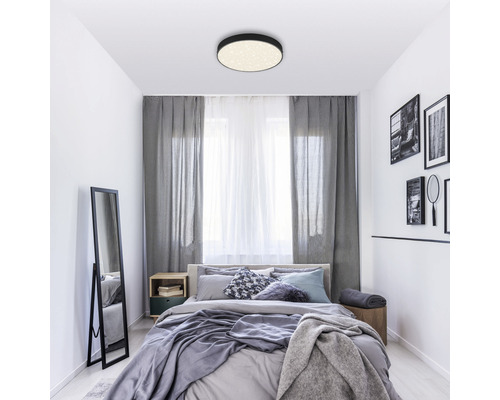 Chambre avec lit, rideaux et plafonnier rond