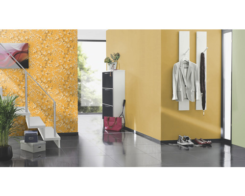 Couloir avec escalier, meuble à chaussures, porte-manteau et papier peint floral.