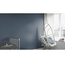 Helle, moderne Schlafzimmereinrichtung mit Schaukelstuhl, Bett und blau gestrichener Wand