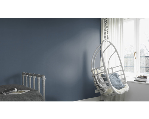 Helle, moderne Schlafzimmereinrichtung mit Schaukelstuhl, Bett und blau gestrichener Wand