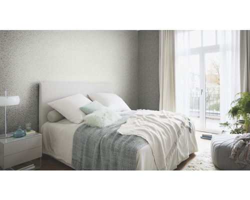 Schlafzimmer mit Bett, Nachttisch und gemusterter Tapete