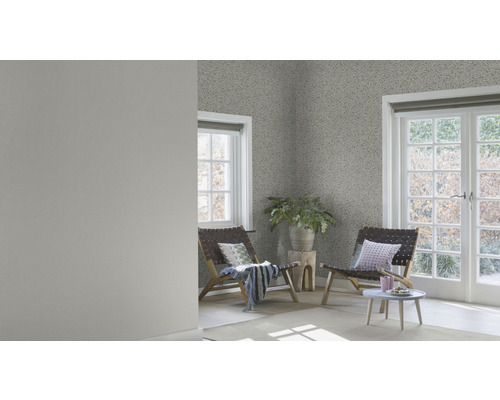 Heller Raum mit gemusterter Tapete, zwei Holzstühlen und einem kleinen Tisch