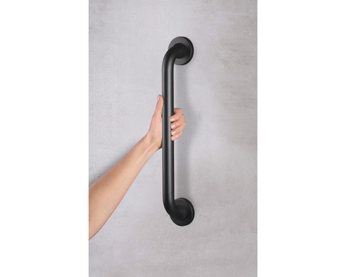 Une main tient une barre d''appui noire, pour le soutien et la sécurité dans la salle de bain