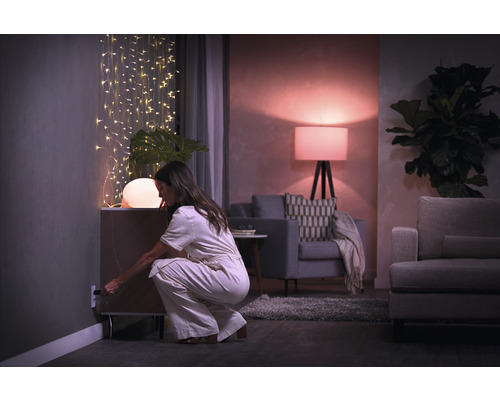 Femme branchant une lampe dans un salon avec des guirlandes lumineuses