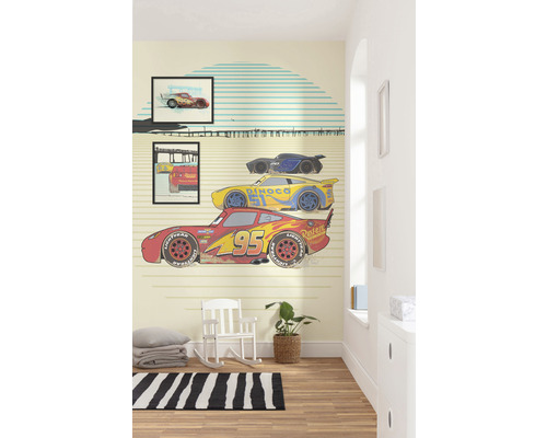 Chambre d''enfant avec papier peint mural inspiré du film Cars, avec un fauteuil à bascule et un tapis
