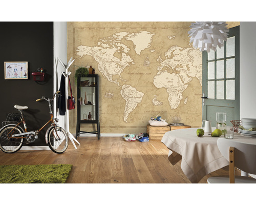 Intérieur avec papier peint carte du monde, vélo, table, chaise, commode et décorations.