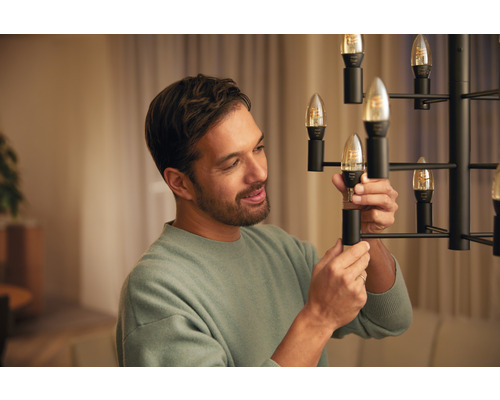 Un homme remplace une lampe LED dans un lustre