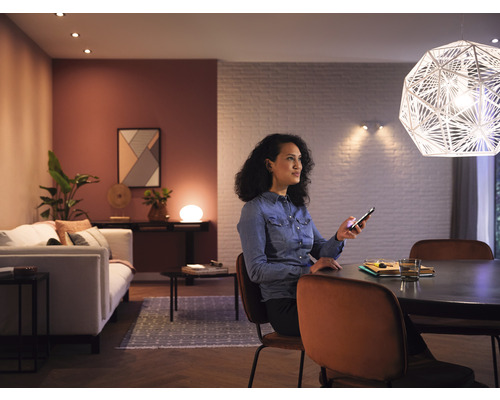 Salon avec éclairage, femme avec smartphone à table
