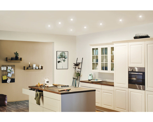 Cuisine claire avec îlot de cuisine, placards intégrés et plafonniers.