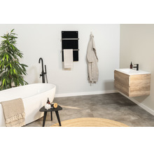 Salle de bains avec baignoire îlot, meuble-lavabo, sèche-serviettes et décorations pour une ambiance claire et conviviale.