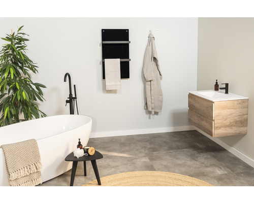 Salle de bains avec baignoire îlot, meuble-lavabo, sèche-serviettes et décorations pour une ambiance claire et conviviale.