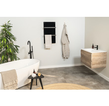 Salle de bains lumineuse avec baignoire îlot, lavabo et sèche-serviettes