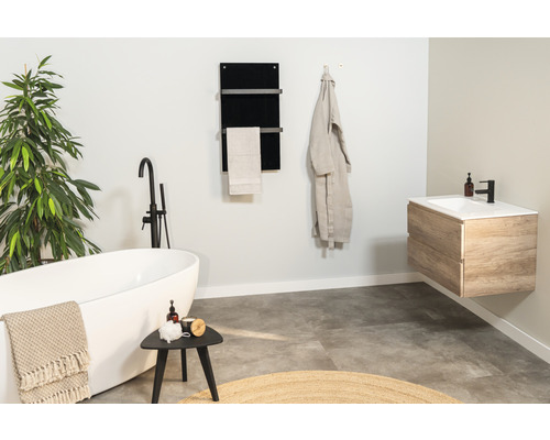 Salle de bains lumineuse avec baignoire îlot, lavabo et sèche-serviettes