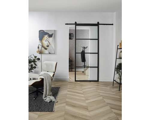 Wohnraum mit Schiebetür aus Glas und Metall, Sessel und Dekoration