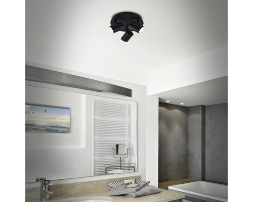 Moderne Badezimmerszene mit schwarzer Deckenleuchte mit Strahlern, Spiegel und Waschtisch