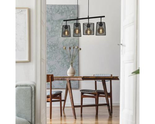 Esszimmer mit Holztisch, Stühlen und einer Hängelampe mit vier Leuchten in einem Metallgitter.