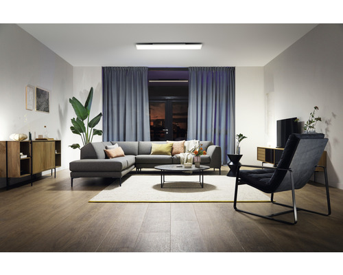 Wohnzimmer mit grauer Couch, Couchtisch, Sessel und Deckenleuchte