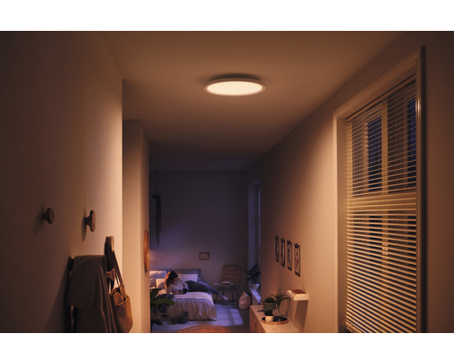 Couloir avec plafonnier rond, porte-manteau et vue sur la chambre