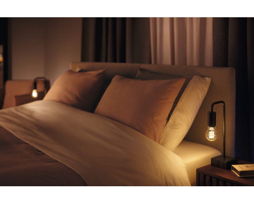 Chambre avec lit, coussins et lampe de chevet
