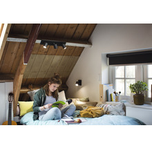Chambre mansardée lumineuse avec spots de plafond et personne en train de lire