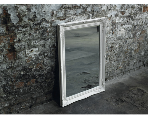 Miroir rectangulaire avec cadre blanc appuyé contre un mur