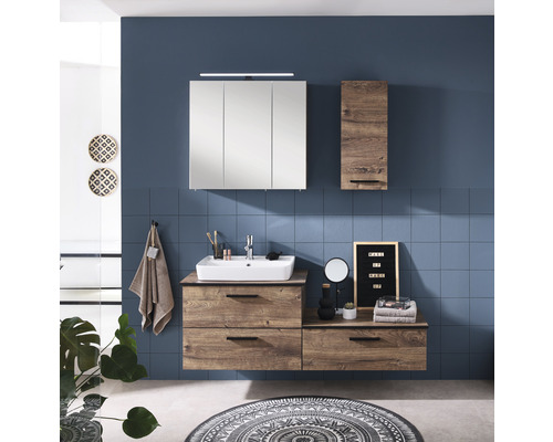Helles Badezimmer mit Waschtisch, Spiegelschrank und Hochschrank im Holzdekor vor blauer Wand.