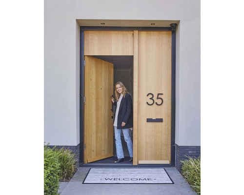 Eine einladende Haustür mit Hausnummer, Briefkasten und Fussmatte mit Willkommensgruss