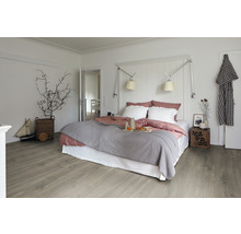 Chambre claire avec lit, table de chevet et plancher en bois