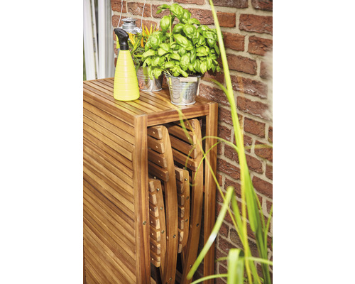 Table en bois avec chaises pliantes, vaporisateur et pots d''herbes aromatiques à l''extérieur.